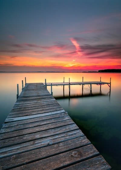 日落时平静水面上的褐色木质船坞